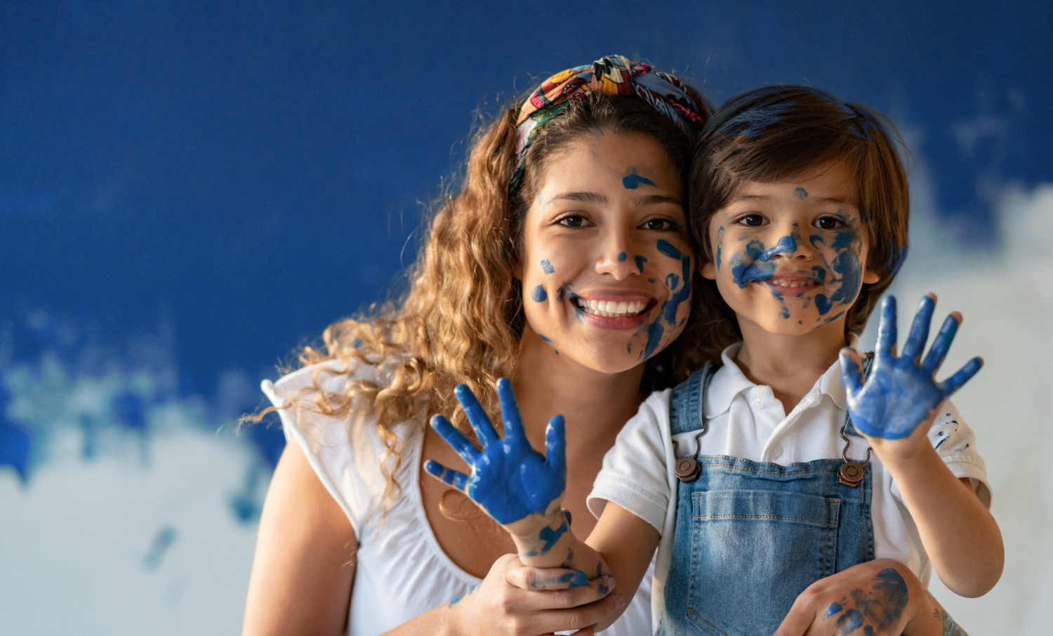 Happy mother and son having fun playing with paint while their house interior is painted